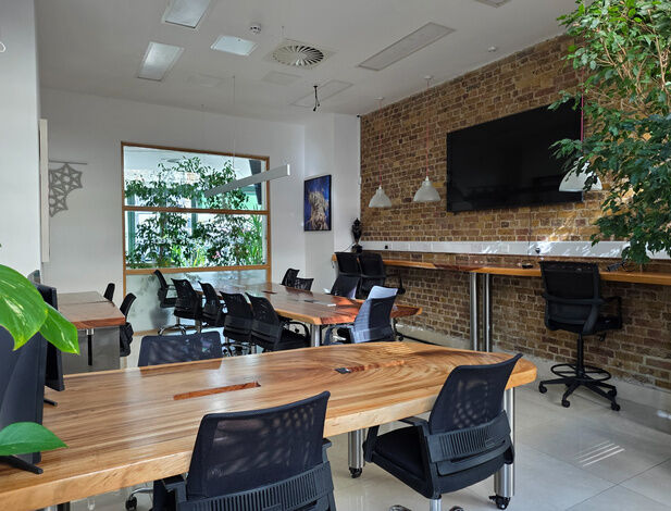 Team workspace at Camden Gateway with timber desks, a brick wall and a wall screen
