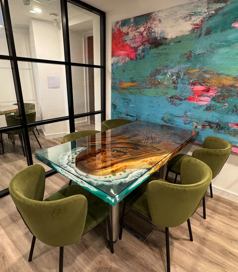 Meeting room at Camden Gateway with a resin and timber table, green chairs and a large painting