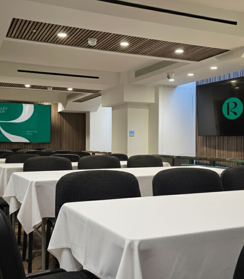 Conference room at Camden Gateway laid out with clothed tables and black chairs