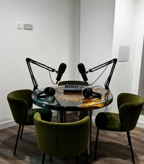 Round table with four microphones and green chairs at Camden Gateway