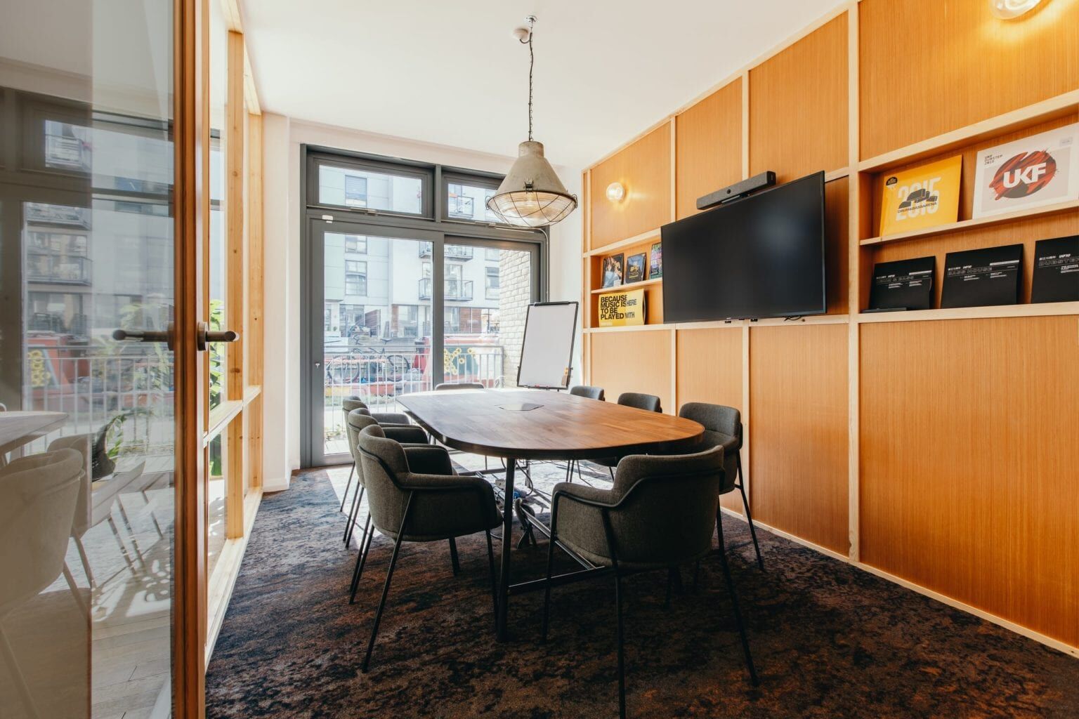 Nova meeting room at The Halley with a round table, chairs and a wall screen beside the canal windows