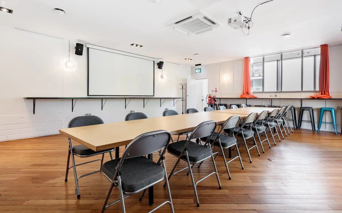 The Gallery event space at The Halley laid out with a long table, chairs and a projector screen