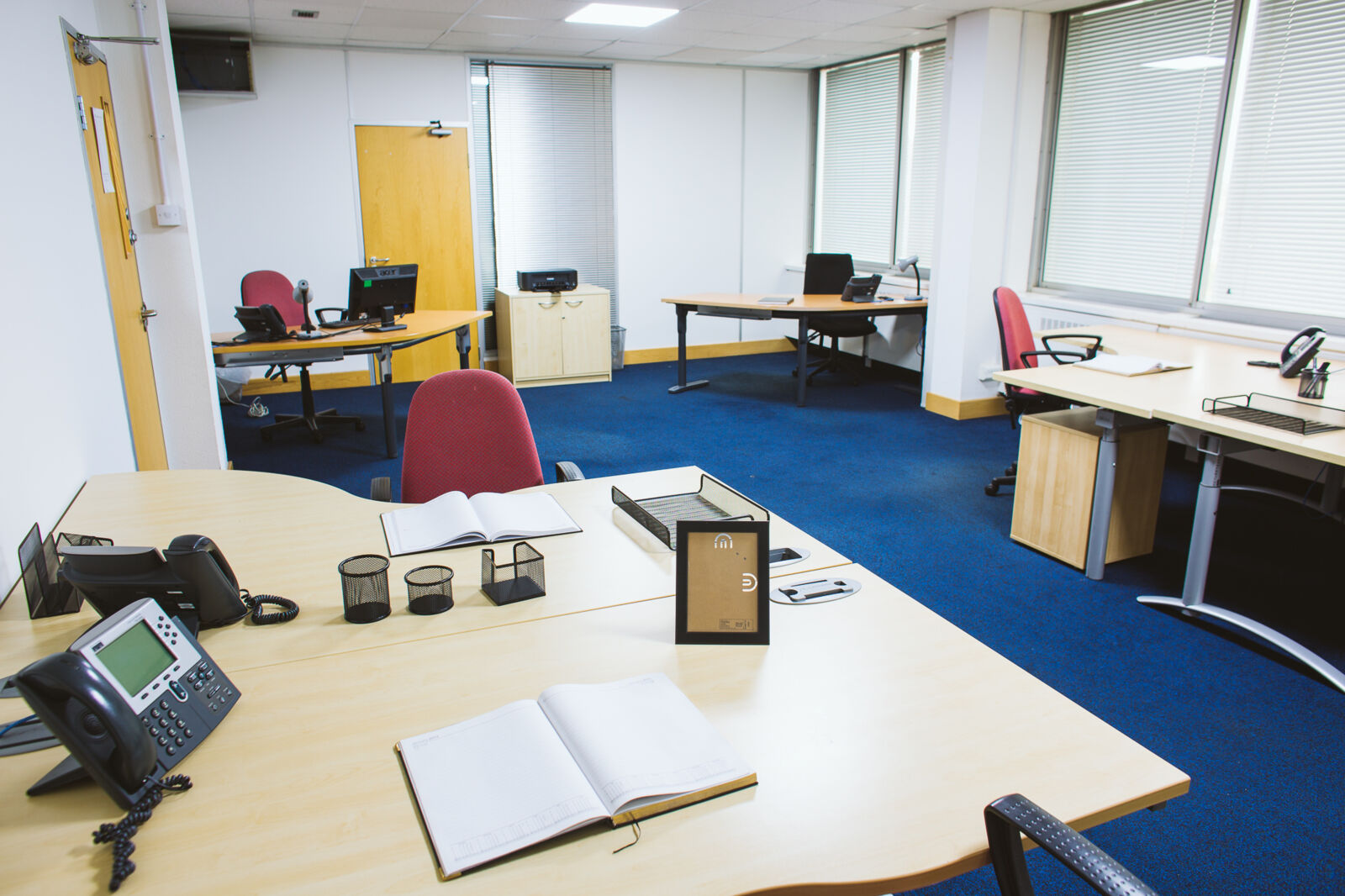 Furnished private office suite at Vista Centre with desks, phones and blue carpet